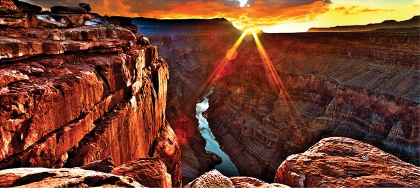 Sunrise over Toroweap in the Grand Canyon with a sunburst above cliffs and the Colorado River below