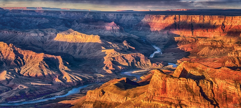 Golden light across Grand Canyon cliffs and ravines at Moran Point with a slender river below